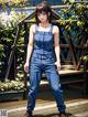 A woman in a blue jumpsuit standing on a wooden deck.