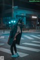 A woman wearing a cat mask standing in the middle of a street.