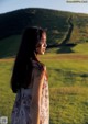 A woman in a floral dress standing in a field.