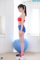 A woman in a red top and blue shorts standing on a blue ball.