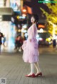 A woman in a pink dress is walking down the street.