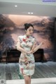 A woman in a cheongsam is pointing at something.