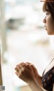 A woman looking out of a window with her hands clasped together.