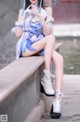 A woman in a blue and white outfit sitting on a ledge.