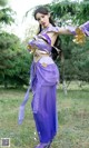A woman in a purple and gold outfit is posing for a picture.