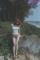 A woman in a white tank top standing on a concrete wall.